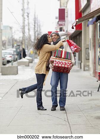 Stock Image - African couple kissing and carrying Christmas presents. Fotosearch