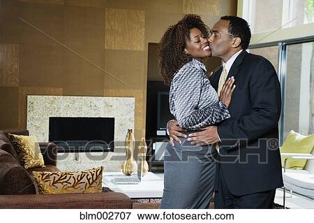 Stock Photo - African couple kissing in modern living room. Fotosearch