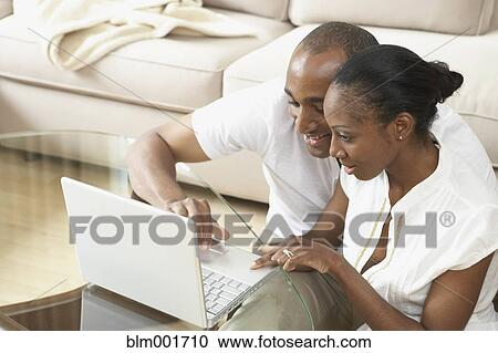 African couple looking at laptop in livingroom View Large Photo Image Stock Image - African couple looking at laptop in livingroom. Fotosearch