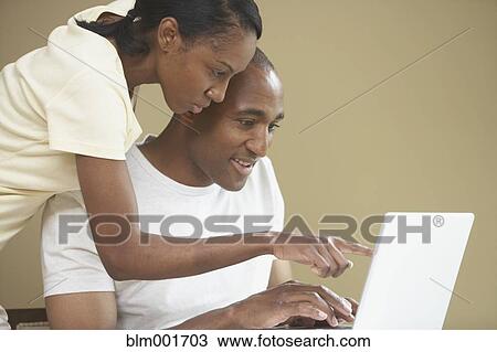 Stock Image - African couple pointing at laptop. Fotosearch