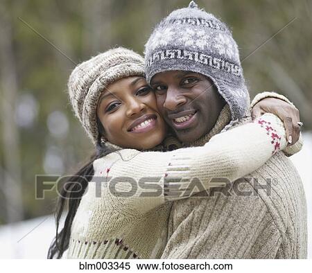 Stock Photography - African couple wearing hats and sweaters hugging. Fotosearch