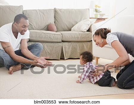 Stock Image - African couple with baby in living room. Fotosearch