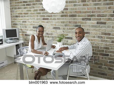 Stock Image - African couple with laptop and calculator at table. Fotosearch