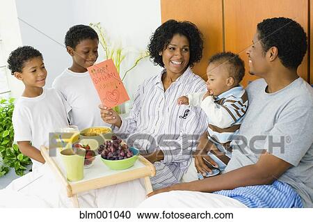 Stock Image - African family giving mother birthday card. Fotosearch