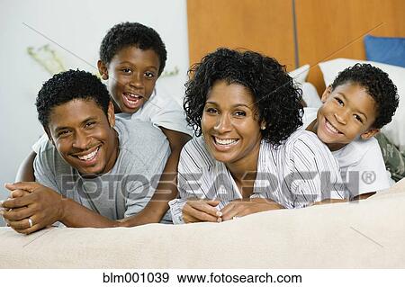 Stock Photo - African family laying on bed together. Fotosearch