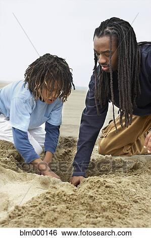 African father and son digging in sand View Large Photo Image Stock Photograph - African father and son digging in sand. Fotosearch