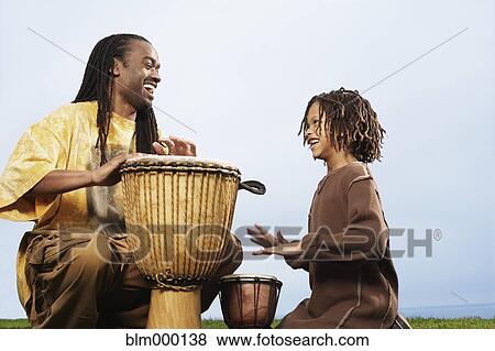 Stock Photo - African father and son playing drums. Fotosearch