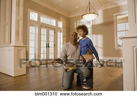 Stock Image - African father and son wearing tool belts. Fotosearch