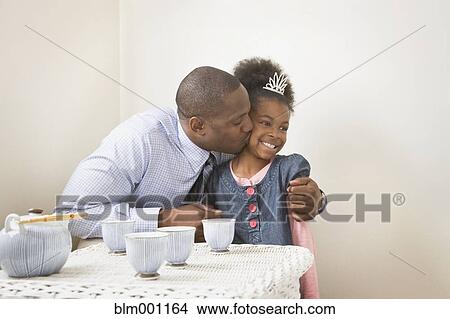 Picture - African father kissing daughter with tiara. Fotosearch