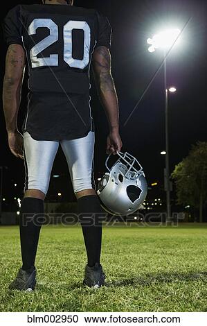 Stock Image - African football player in uniform holding helmet. Fotosearch