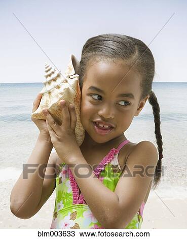 African girl holding conch shell to ear View Large Photo Image Stock Image - African girl holding conch shell to ear. Fotosearch