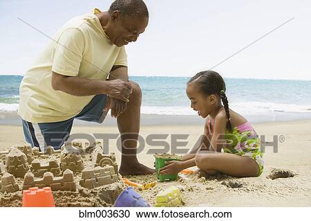 African grandfather and granddaughter building sand castle View Large Photo Image Stock Image - African grandfather and granddaughter building sand castle. Fotosearch