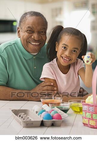 Stock Photograph - African grandfather and granddaughter coloring Easter eggs. Fotosearch