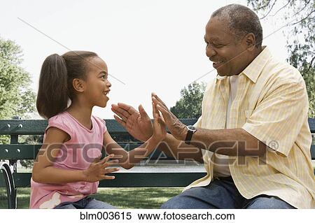 Stock Photography - African grandfather and granddaughter playing patty-cake. Fotosearch
