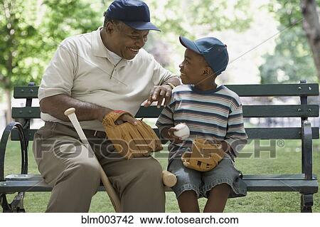 African grandfather and grandson holding baseball equipment on park bench View Large Photo Image Stock Image - African grandfather and grandson holding baseball equipment on park bench. Fotosearch