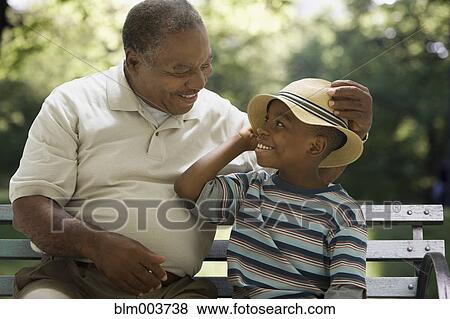 Stock Photo - African grandfather and grandson sitting on park bench. Fotosearch