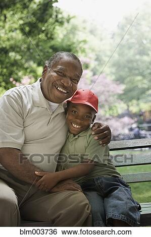 African grandfather and grandson hugging on park bench View Large Photo Image Stock Photograph - African grandfather and grandson hugging on park bench. Fotosearch