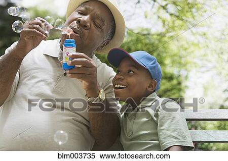 Stock Photography - African grandfather and grandson blowing bubbles. Fotosearch