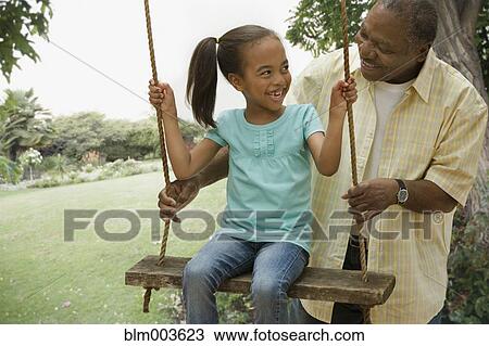 African grandfather pushing granddaughter on swing View Large Photo Image Stock Image - African grandfather pushing granddaughter on swing. Fotosearch