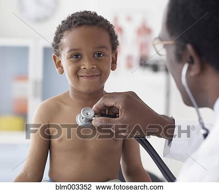 Stock Image - African male doctor examining african boy. Fotosearch