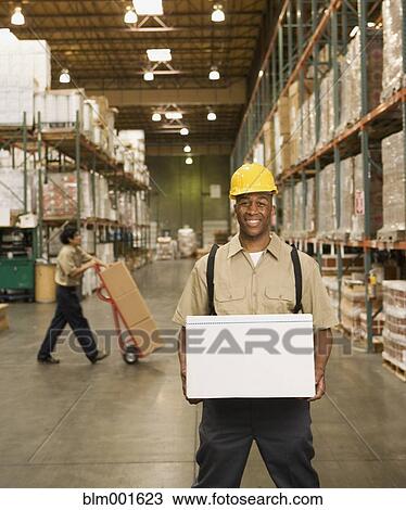 Stock Image - African male warehouse worker with box. Fotosearch