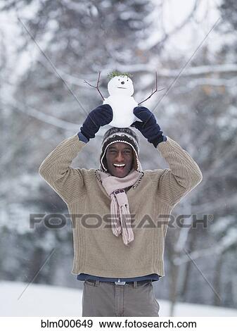Stock Photo - African man balancing miniature snowman on head. Fotosearch