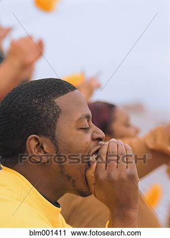 Stock Image - African man cheering at sporting event. Fotosearch