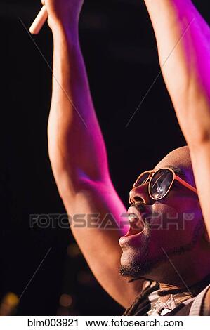 Stock Image - African man cheering with arms raised. Fotosearch