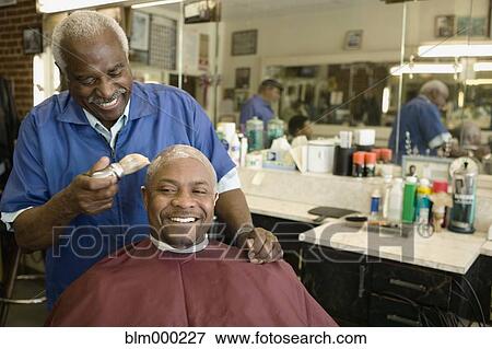 Stock Photo - African man having his head shaved in barbershop. Fotosearch