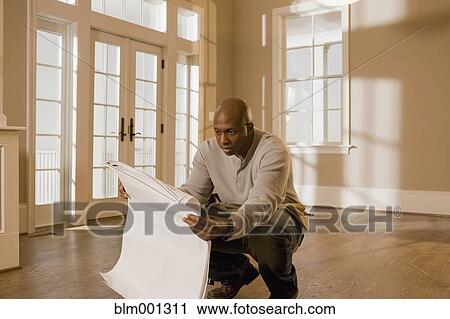 Stock Image - African man holding blueprint. Fotosearch