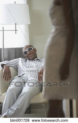 Stock Photo - African man in sunglasses looking at wife in foreground. Fotosearch