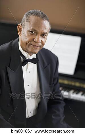 Stock Photo - African man in tuxedo sitting in front of piano. Fotosearch