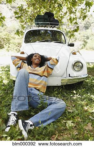 Stock Image - African man laying on hood of car. Fotosearch