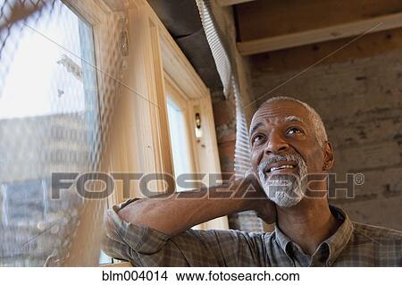 Picture - African man leaning against window. Fotosearch