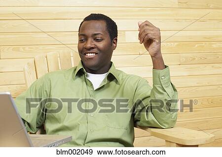 Stock Photo - African man looking at laptop. Fotosearch