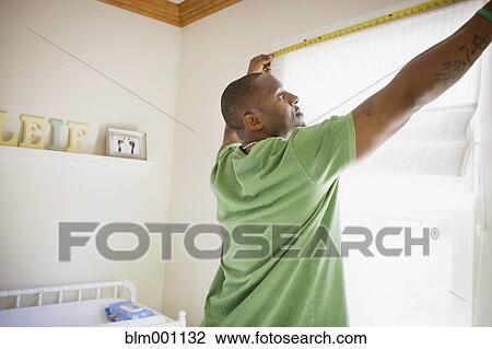 Stock Image - African man measuring window. Fotosearch
