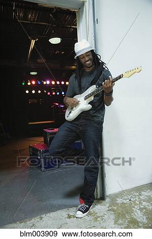 Stock Photo - African man playing electric guitar backstage. Fotosearch