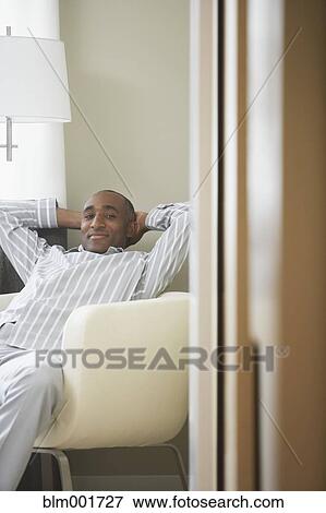 African man sitting in armchair with hands behind head View Large Photo Image Stock Photo - African man sitting in armchair with hands behind head. Fotosearch