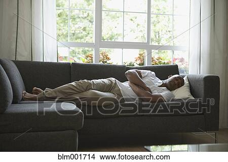 Picture - African man sleeping on sofa. Fotosearch