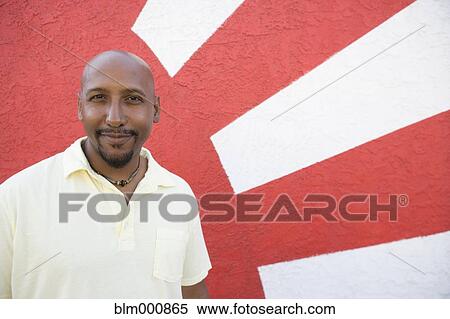 Stock Photography - African man standing be decorative wall. Fotosearch