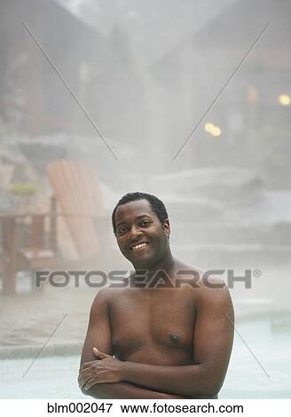 Stock Photo - African man standing in hot tub. Fotosearch