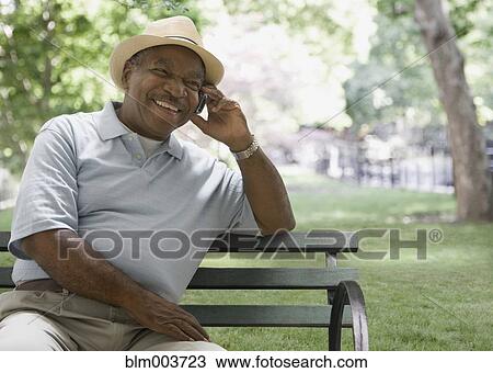 African man talking on cell phone on park bench View Large Photo Image Stock Image - African man talking on cell phone on park bench. Fotosearch