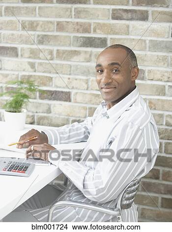 Picture - African man with calculator at table. Fotosearch