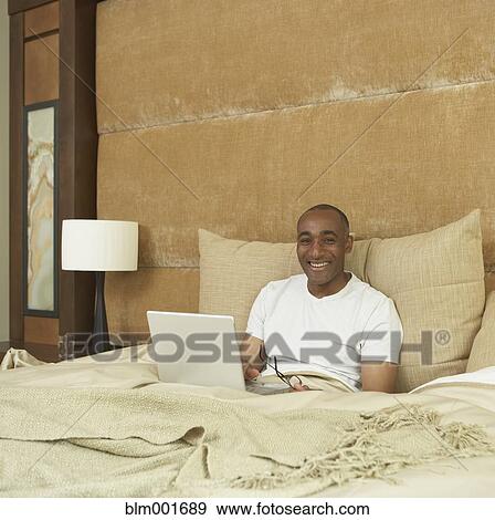 African man with laptop in bed View Large Photo Image Stock Photo - African man with laptop in bed. Fotosearch