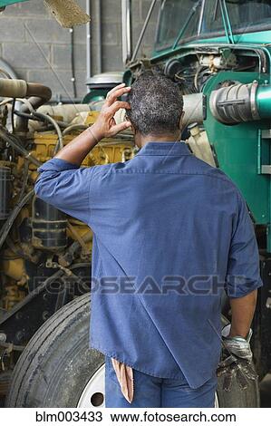 Stock Image - African mechanic in repair shop scratching head. Fotosearch