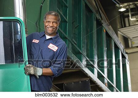 Stock Image - African mechanic standing on dump truck. Fotosearch