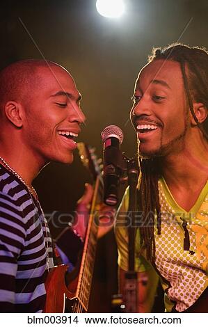 Picture - African men singing and playing guitar onstage. Fotosearch