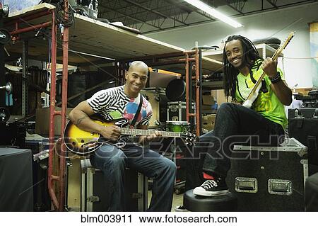 Stock Image - African men with electric guitars in warehouse. Fotosearch