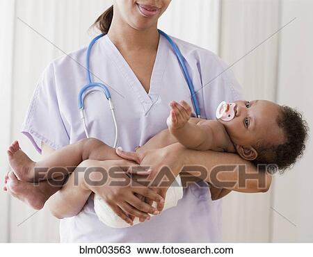 Stock Image - African nurse holding baby. Fotosearch