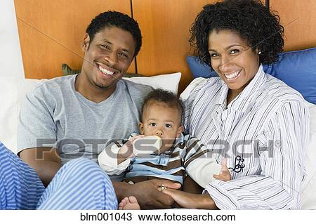 African parents feeding child bottle in bed View Large Photo Image Stock Image - African parents feeding child bottle in bed. Fotosearch